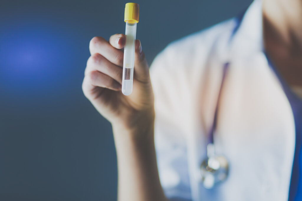 female medical or research scientist or doctor using looking at a test tube of clear solution in a lab or laboratory.